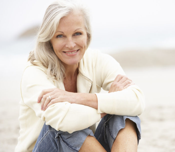 Senior Woman On Holiday Sitting On Winter Beach